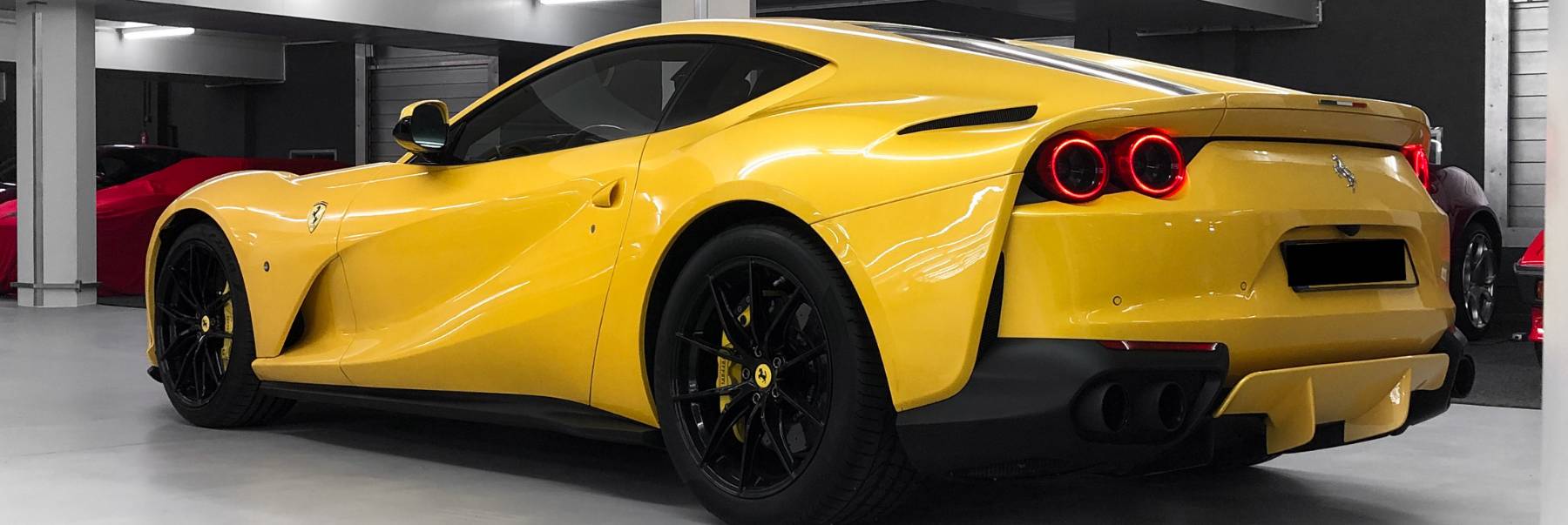 Ein gelber Ferrari von schräg hinten in der HUBRAUM-Halle, daneben weitere Fahrzeuge