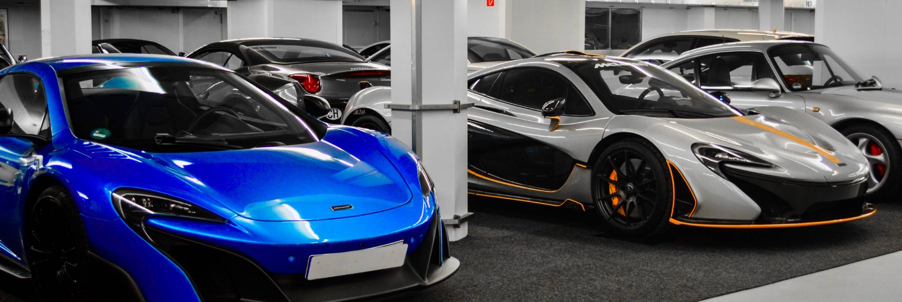 Ein blauer McLaren und ein silberner McLaren P1 nebeneinander auf ihren Stellplätzen in der HUBRAUM-Halle