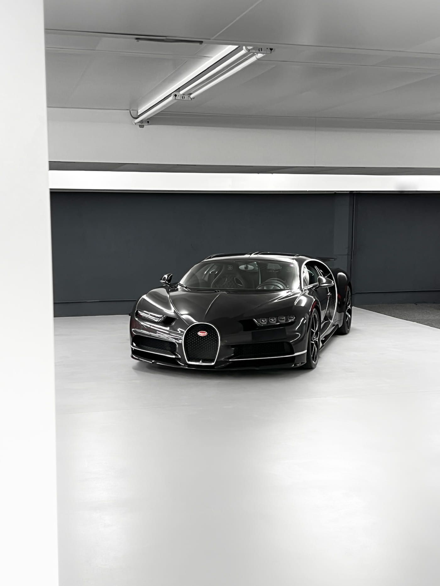 Ein schwarzer Bugatti Chiron allein auf der hellen Fläche der HUBRAUM-Halle