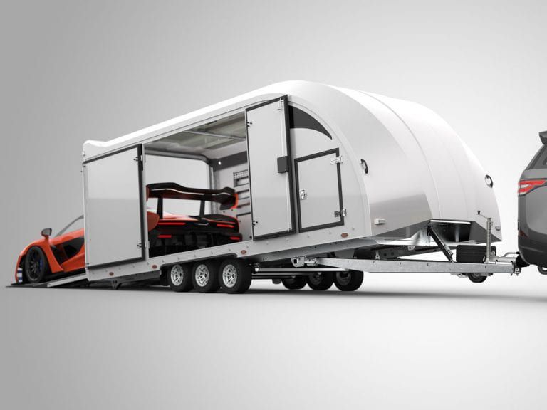 Ein geschlossener Autotransport-Anhänger mit geöffneter Seitentür, darin ein orangefarbener Sportwagen, angekuppelt an ein Zugfahrzeug